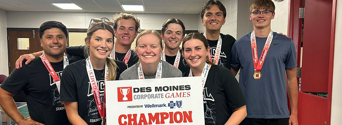 A group of young adults smiling with a sign that says